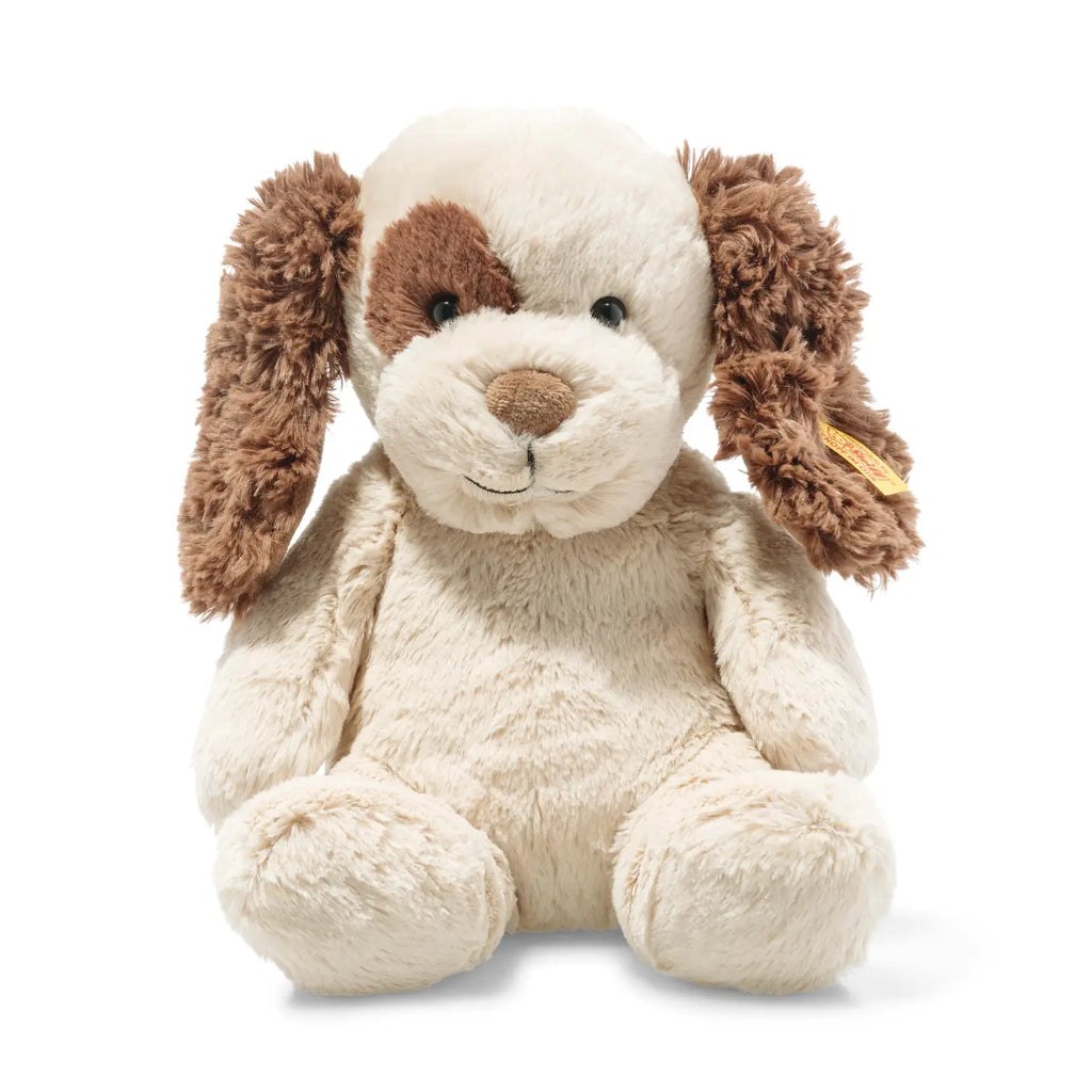 A plush toy rabbit with a white and light brown coat, floppy brown ears, and a gentle, smiling expression. The Steiff stuffed animal is made from cuddly soft plush, sitting upright and isolated on a