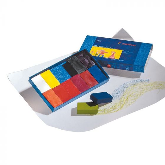 A set of Stockmar Wax Block Crayons Box -12 Assorted beside their packaging, with a partially completed landscape drawing on textured paper featuring mountains and grass.