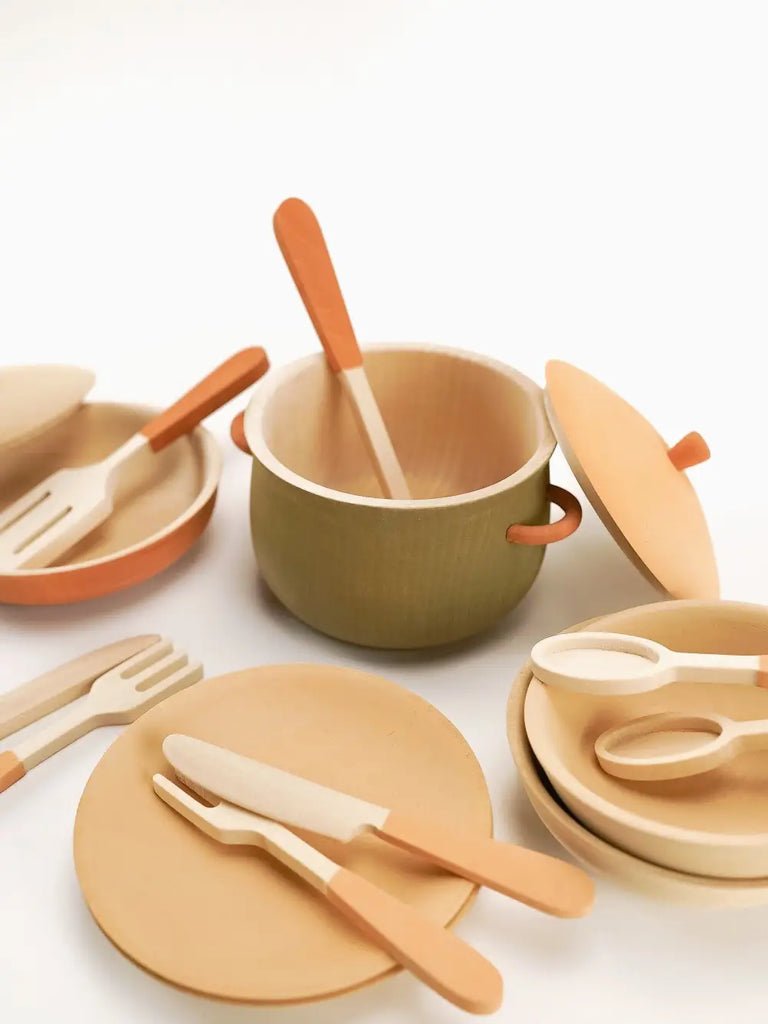 Handmade Wooden Kitchen Essentials - Herbal displayed on a white background. Includes bowls with lids, plates, and utensils, all in soft natural colors. Ideal as a non-toxic educational play set for