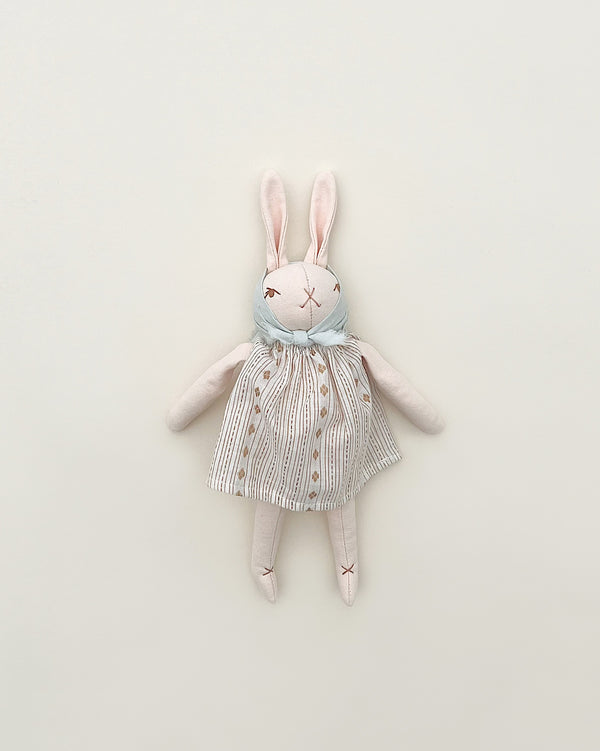 A Polka Dot Club Little Rabbit in Headscarf and Dress toy with a striped dress and a hand embroidered blue scarf, lying flat on a plain light background. The rabbit has stitched eyes and mouth, giving it a crafted look.
