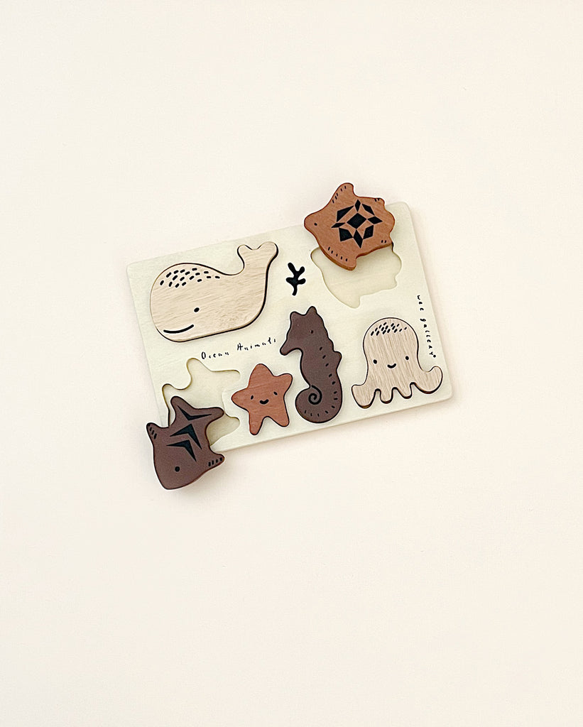 A Wooden Tray Puzzle - Ocean Animals featuring educational fun sea creature shapes like a whale, turtle, starfish, seahorse, stingray, and octopus on a soft beige background.