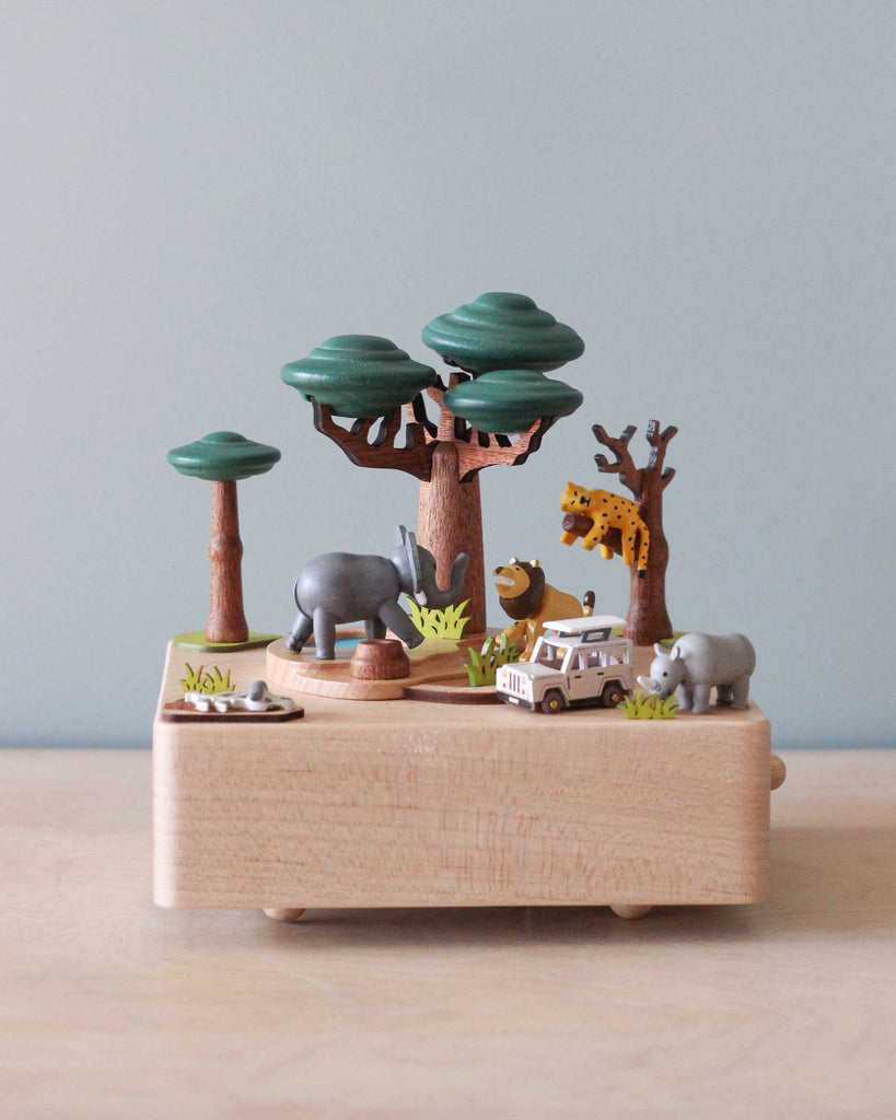 Wooden music box with a tree in the middle with African animals. A small wooden jeep going around the music box.