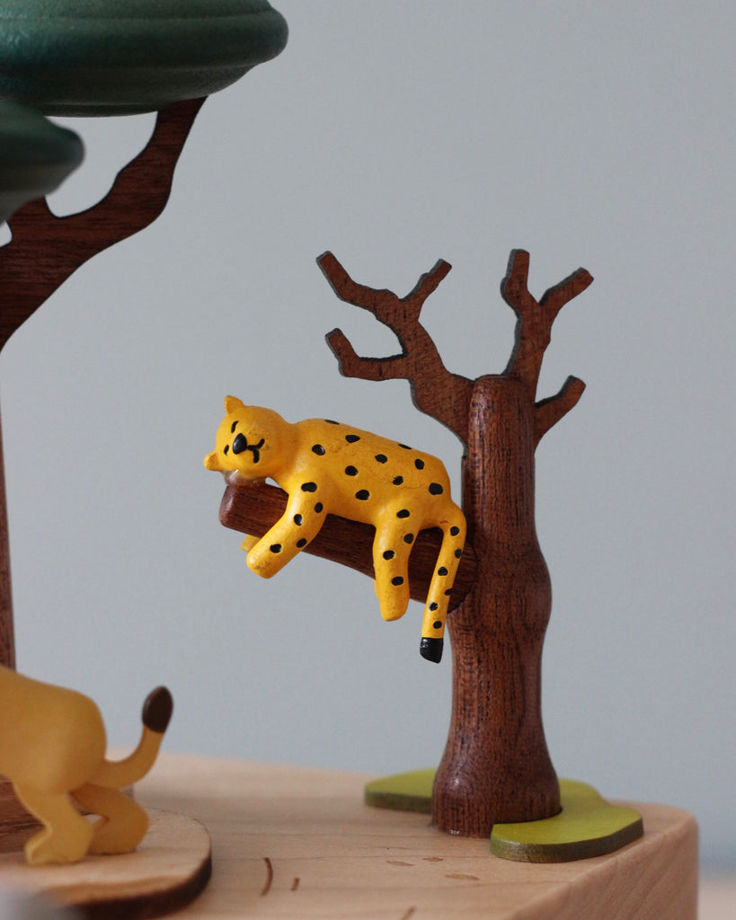 Wooden music box with a tree in the middle with African animals. A small wooden jeep going around the music box. 