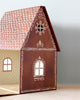 A small, intricately designed wooden house model resembles a Maileg Cardboard Gingerbread House, with a steeply pitched, tiled roof and ornate exterior details. The front boasts a large window with a circular design above it, while the interior walls are adorned with light patterned wallpaper—perfect for holiday surprises with micro Maileg friends.
