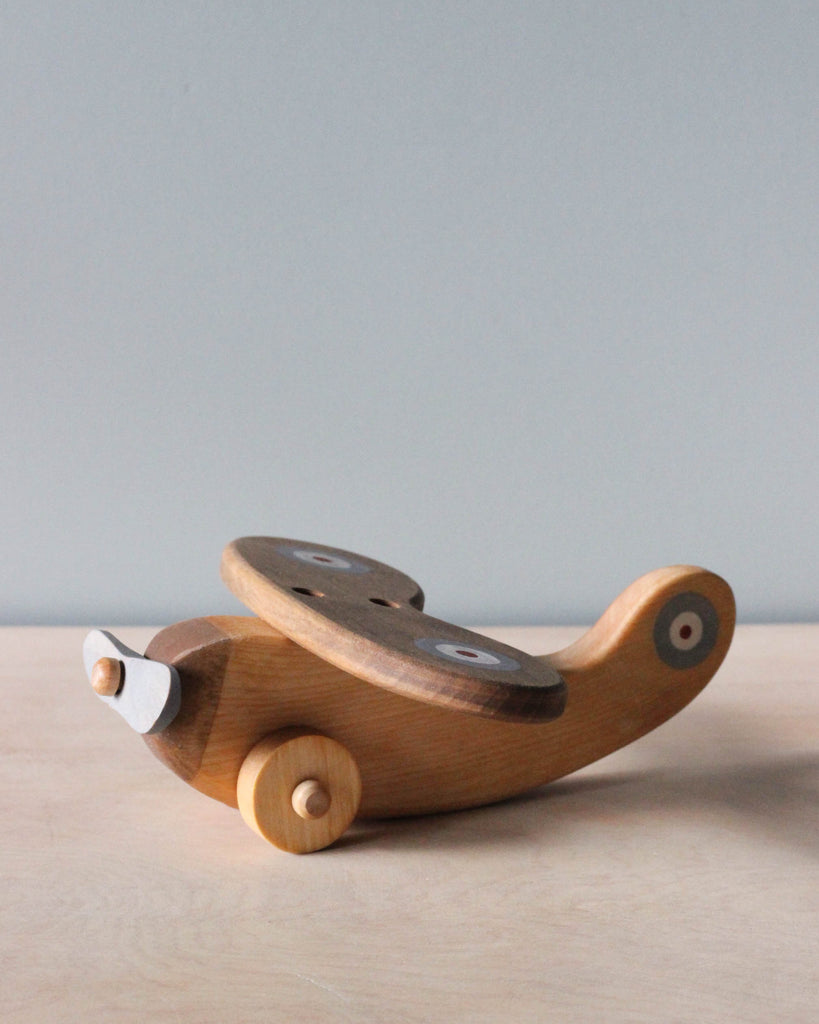 Wooden airplane with light blue propeller on natural color counter and light blue background.