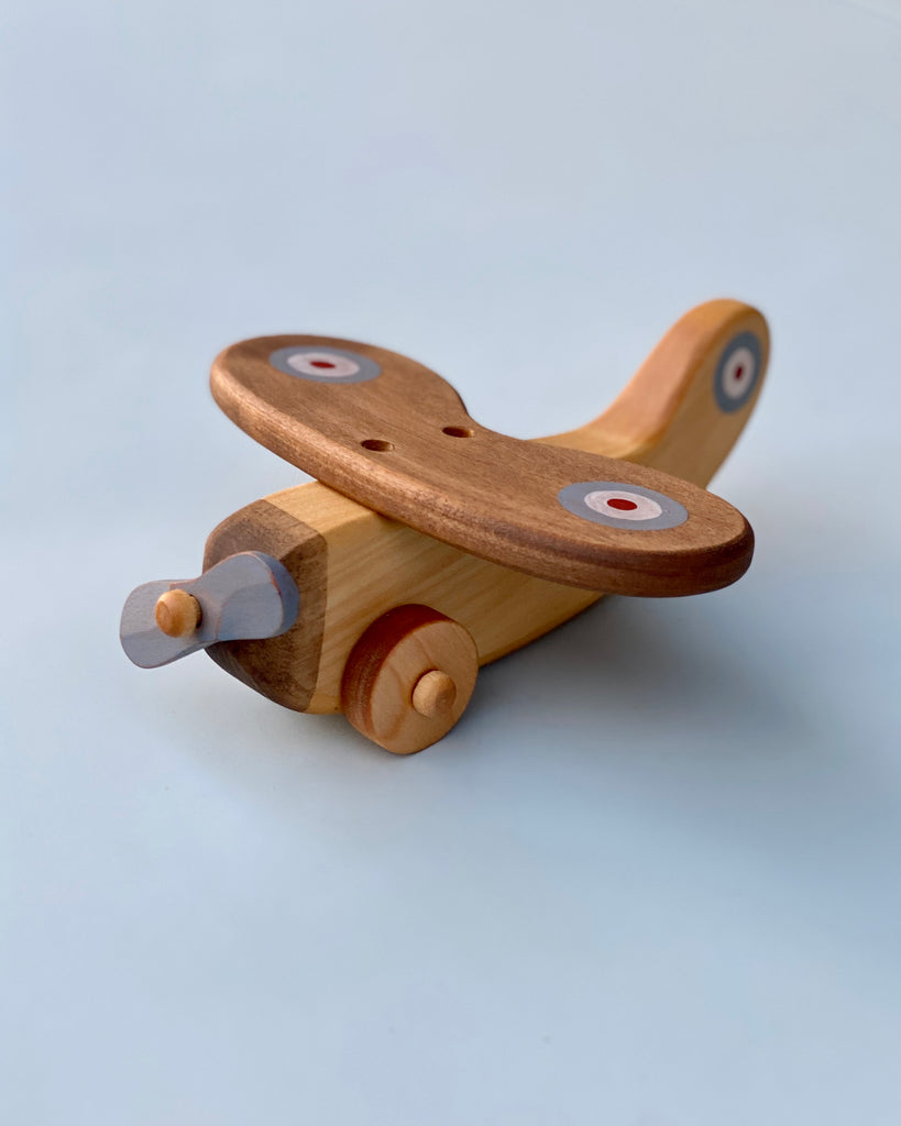 Wooden airplane with light blue propeller. Light blue background.
