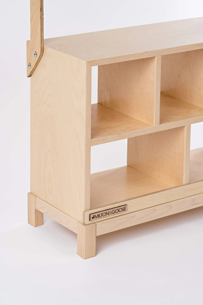 A light-colored wooden shoe rack with two shelves and a small label saying "Milton & Goose Market Stand" at the bottom. The rack is handcrafted in the USA, featuring a simple structure with visible screws.