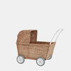 Olli Ella Rattan Doll Stroller with a white handle and four grey wheels, isolated on a plain white background. The stroller has a traditional, woven design with an openable hood.