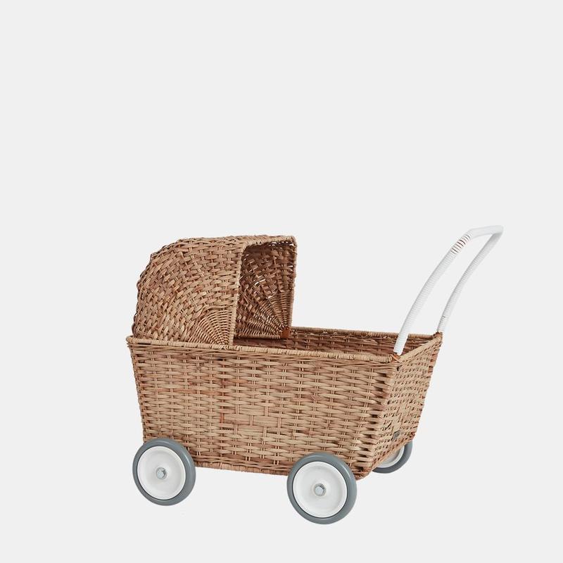 Olli Ella Rattan Doll Stroller with a white handle and four grey wheels, isolated on a plain white background. The stroller has a traditional, woven design with an openable hood.