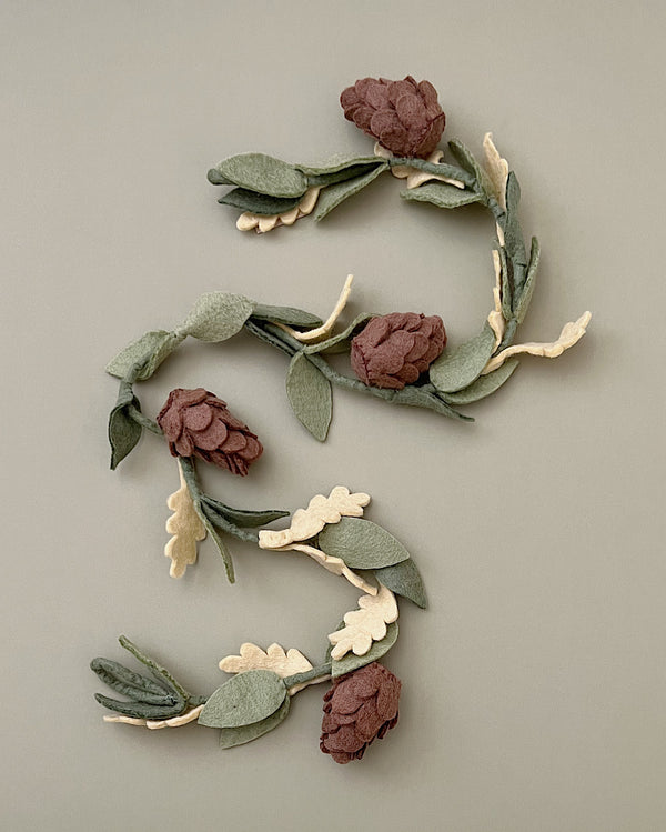 A number "5" crafted from Felt Christmas Garland, arranged on a muted gray background. The design is eco-friendly and botanical, emphasizing natural elements.