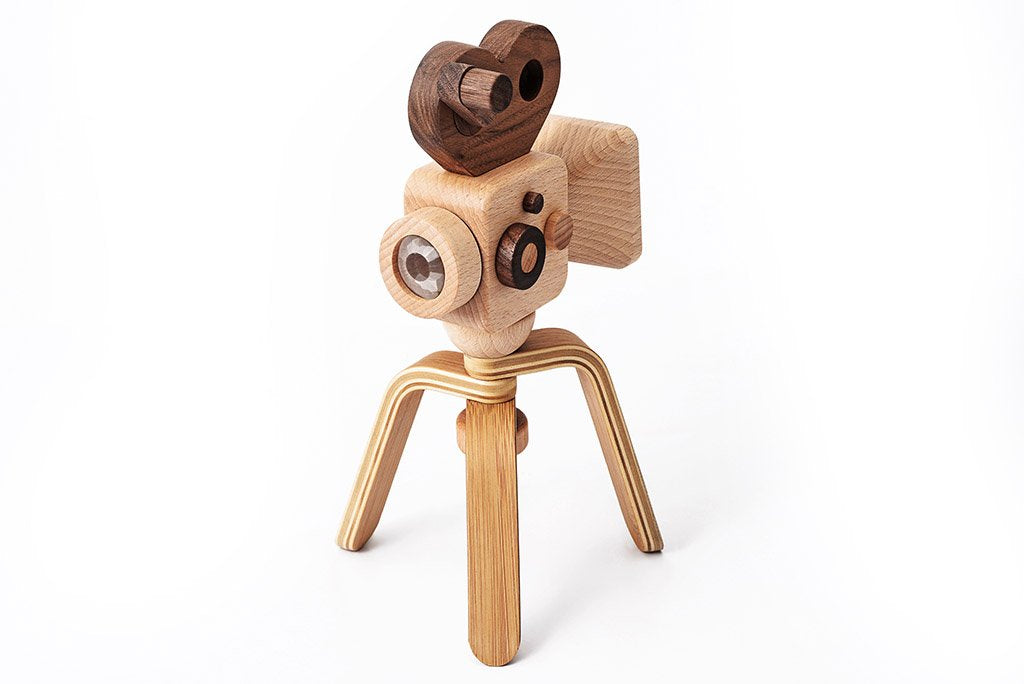 A Father’s Factory wooden toy camera with tripod legs and a playful design, featuring rounded elements, set against a white background.