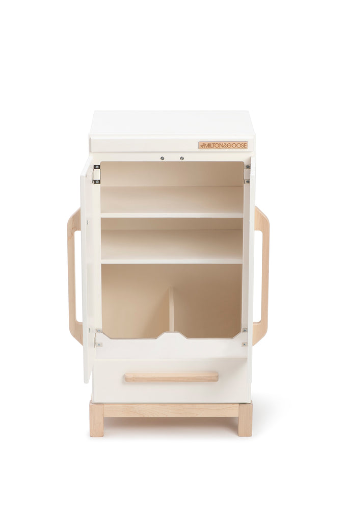 A portable, modern beige and white play kitchen station designed for children, featuring open shelving, a faux oven door, and sustainable wooden details, isolated on a white background.