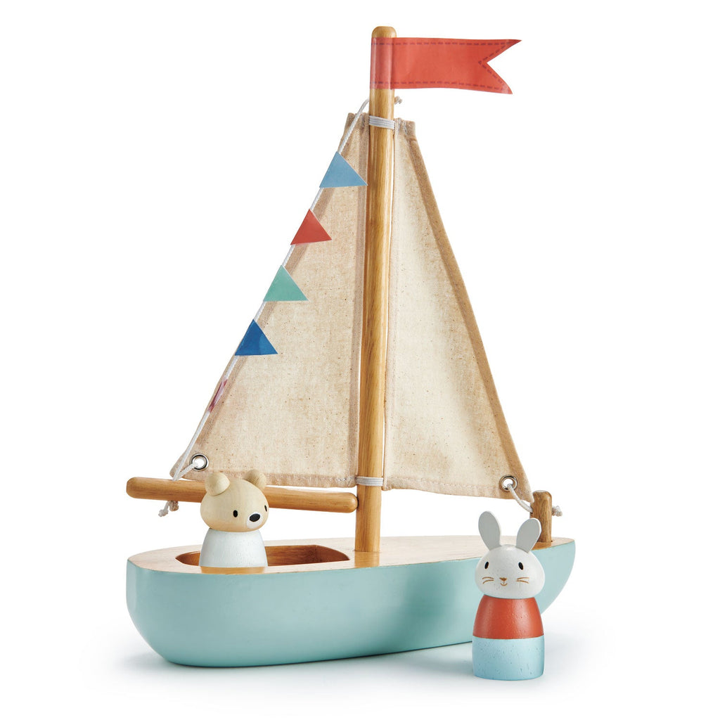 A traditional Wooden Sail Boat painted light blue with beige fabric sails, featuring wooden animal figures dressed as a bear and a rabbit as passengers. The boat is decorated with colorful flags on one side.