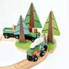 A Wild Pines Train Set featuring a magnetic locomotive and two cargo cars on a loop track, surrounded by three green pine trees, set against a white background.