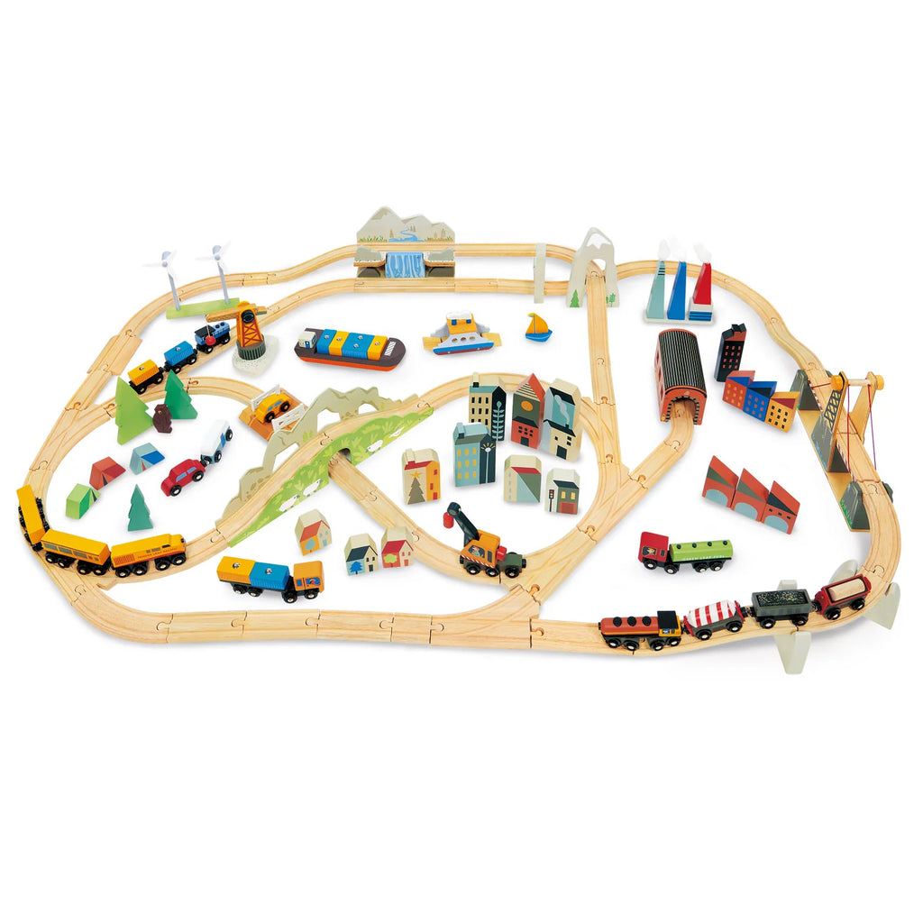 A vibrant Mountain View Train set laid out on a white background, featuring multiple loops of tracks, colorful trains, assorted vehicles, buildings, and trees.