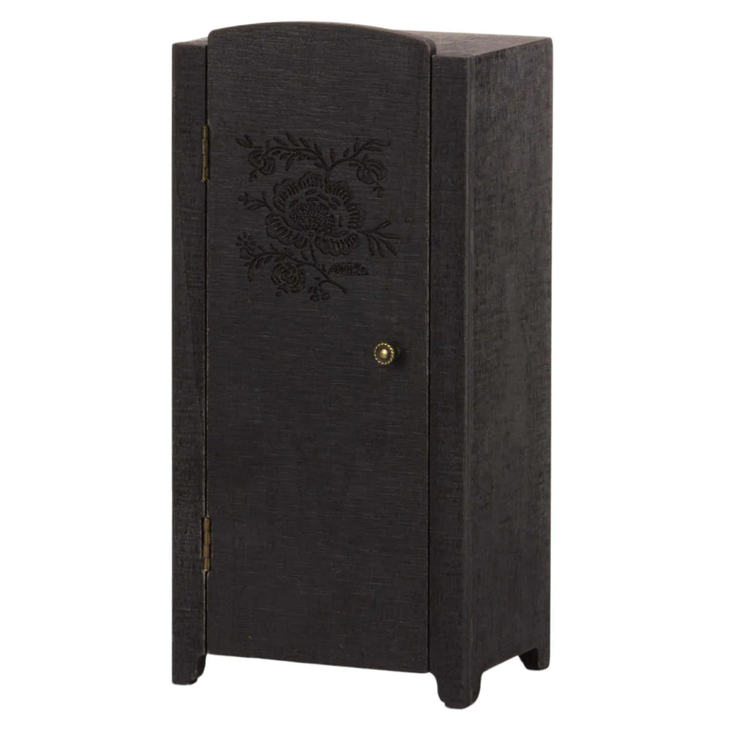 A tall, narrow black Maileg Miniature Closet with an intricately carved floral pattern and a brass knob on its single door, crafted from FSC wood and isolated on a white background.