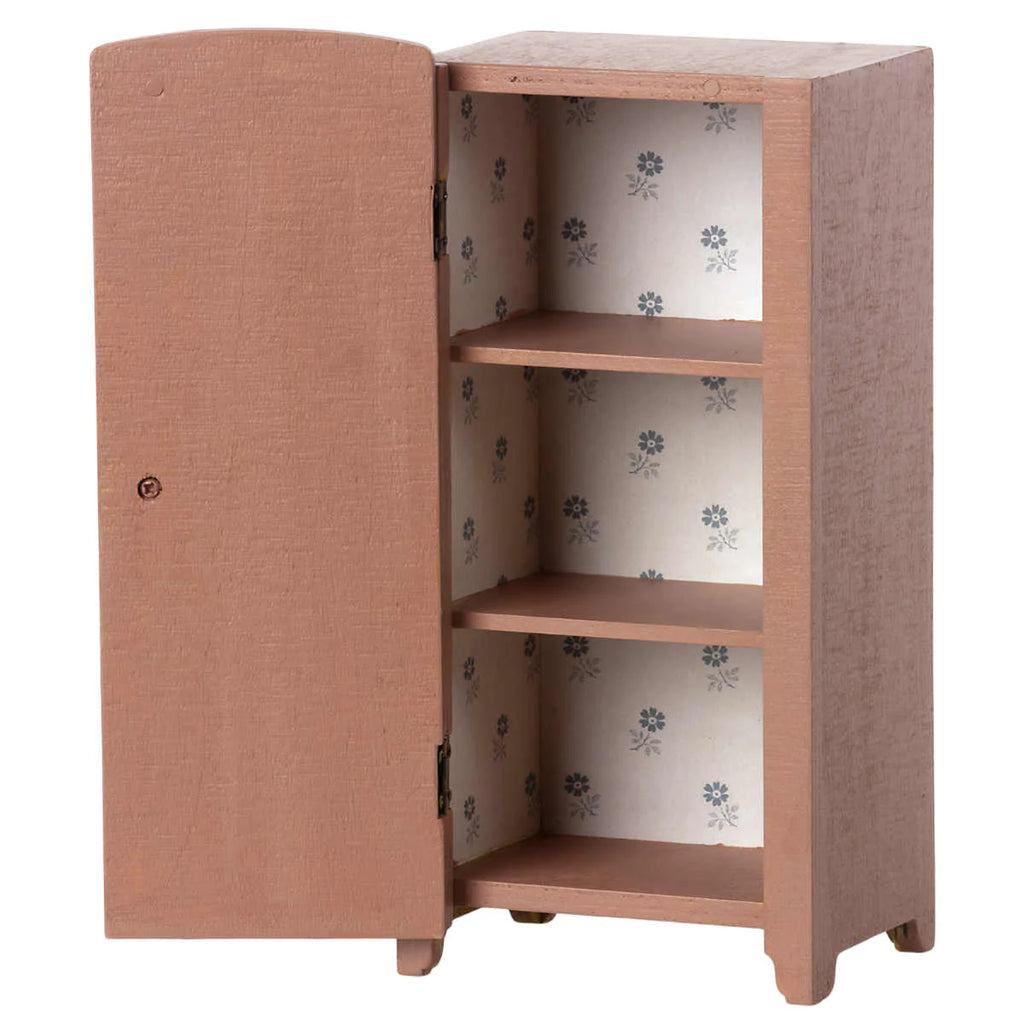 A small, peach-colored Maileg Miniature Closet crafted from FSC-certified wood, with one door partially open, revealing three shelves lined with paper featuring a blue floral pattern.