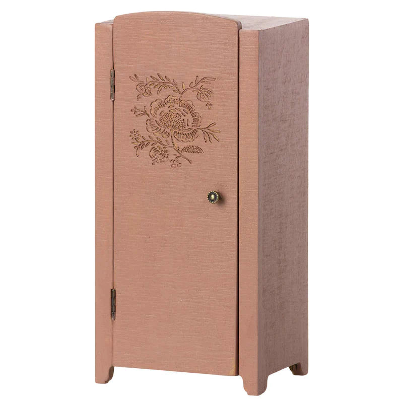 A tall, narrow pink Maileg Miniature Closet with a floral carving on its front door and a small, round handle, standing against a plain background.