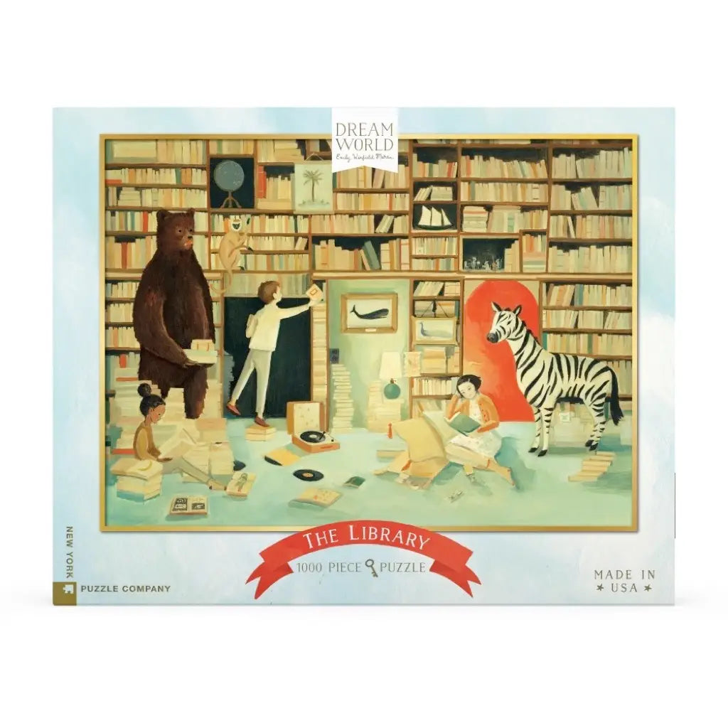 An illustrated jigsaw puzzle box depicting a whimsical library scene with a bear, a zebra, and children among strewn books and puzzle pieces, titled "The Library" by Emily Winfield Martin.