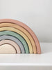 A Handmade Rainbow Stacker - Pastel consisting of arches in pastel colors of pink, orange, yellow, green, blue, and light purple, stacked in size order on a white surface against a white background.