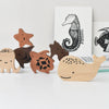 The Wooden Tray Puzzle - Ocean Animals, including an octopus, bear, triceratops, and whale from the Ocean set, displayed in front of books with marine animal illustrations.