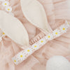 Close-up of a Meri Meri Peach Tulle Bunny Costume adorned with white daisy flowers on a pink frilly background, perfect for an Easter costume.