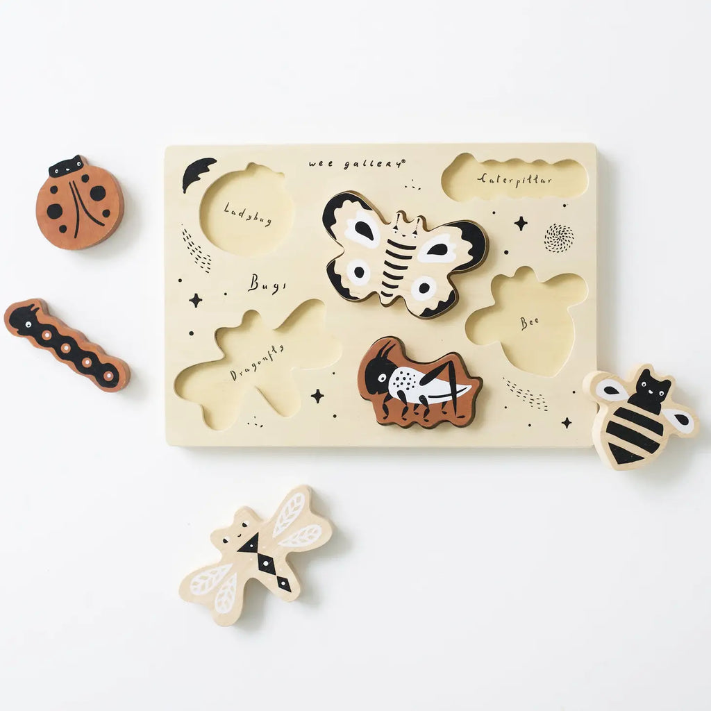 A Wooden Tray Puzzle - Bugs set with insect shapes including a ladybug, caterpillar, butterfly, dragonfly, and bee, displayed on a white surface. The sustainably sourced rubberwood puzzle board