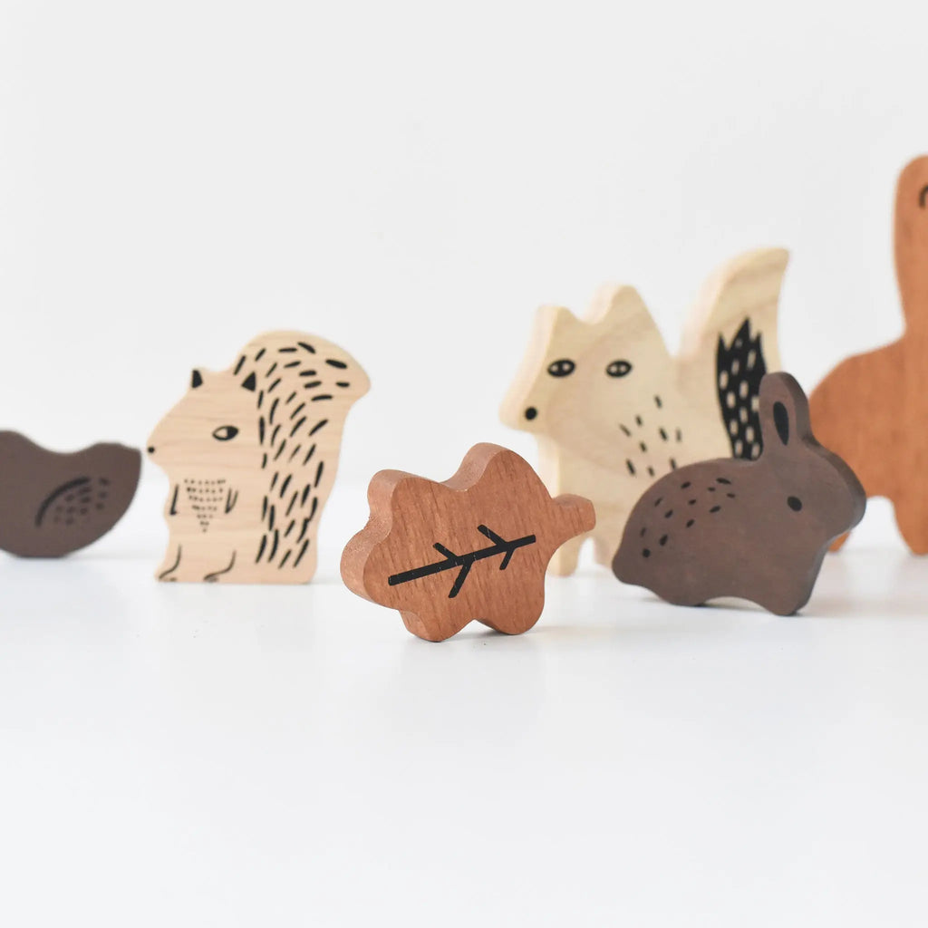 A collection of sustainably sourced rubberwood Wooden Tray Puzzle - Woodland Animals, including a hedgehog, wolf, squirrel, and others on a white background, with a small tree-shaped piece in the foreground.