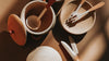 Top-down view of various Herbal handmade wooden kitchen utensils and bowls cast in soft light, with shadows creating an artistic contrast.