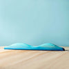 A soft, blue gel wrist rest on a Set of Handmade Wooden Palm Trees & Waves against a light blue background, designed to provide ergonomic comfort while typing.