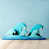 Handmade decorative Set of Handmade Wooden Palm Trees & Waves, artistically crafted to resemble the ocean, displayed against a soft blue background on a wooden surface.