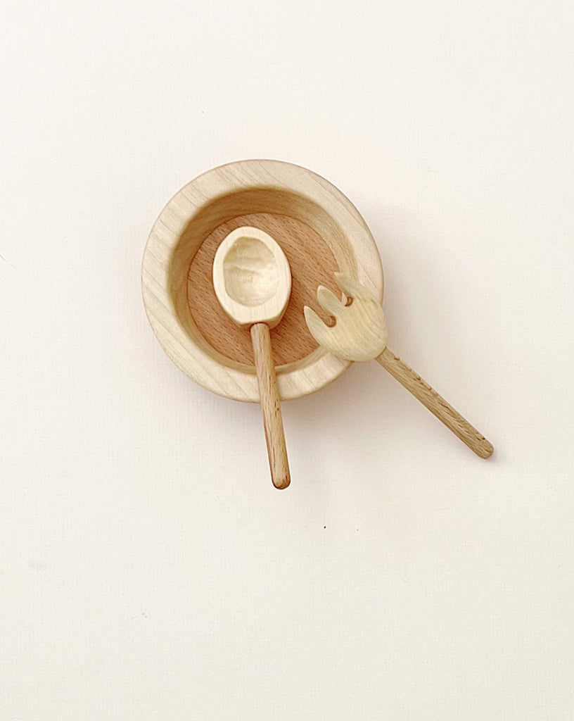 A Handmade Pretend Dinnerware Set with a matching handmade wooden cutlery on a white background. The spoon and fork have whimsical, cartoonish handles.