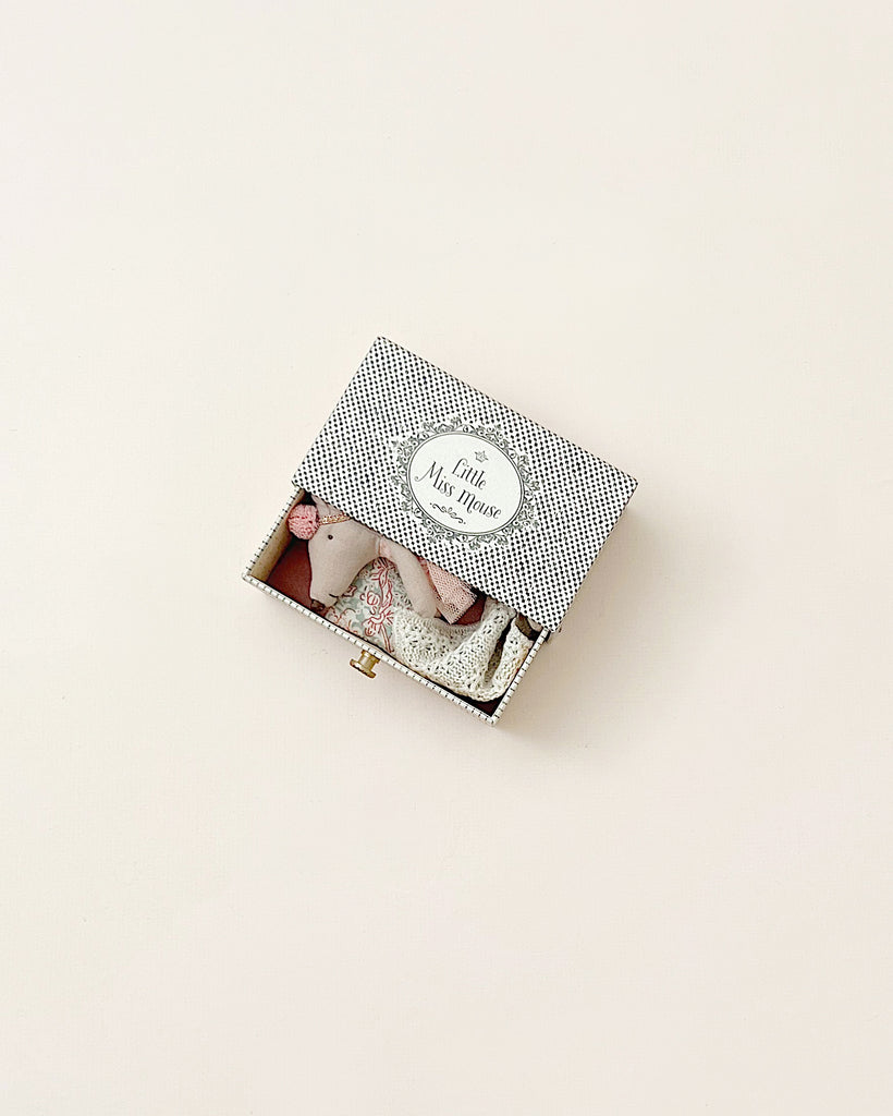 A small, open gift box containing a Maileg Dancing Mouse in Daybed, against a neutral background. The box lid features a decorative black and white pattern with a label that reads "Maileg Dancing Mouse in Daybed".