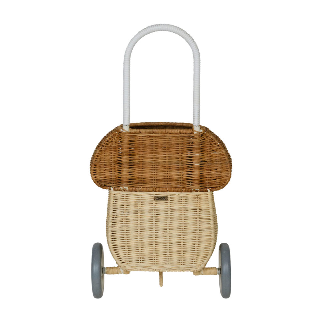 A traditional hand-woven Olli Ella Rattan Mushroom Luggy - Natural serving cart with two tiers and wheels, displayed against a dark background. The cart features a curved handle for easy maneuvering.