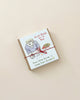 A small gift-wrapped Non-Toxic 64 Piece Crayon Rocks tied with a red string on a light beige background. The cover illustrates a cartoon sketch of a boy with a speech bubble saying "just books. I'm a bot.