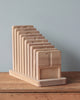 A beech wood letter holder with multiple slots, each slot with a curved top, displayed on a wooden table against a plain blue background - The Original Wooden Counting Trays - Made in USA.