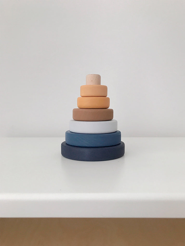 A Mini Wooden Pyramid Stacker - Desert Night with six rings in varying sizes and colors, coated in non-toxic paint, arranged in order from largest at the bottom to smallest on top, set against a plain white background.