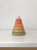 A Mini Wooden Pyramid Stacker - Flower Meadow consisting of six rings in gradient shades from dark green at the base to light orange at the top, painted with non-toxic paint, set against a plain white background.