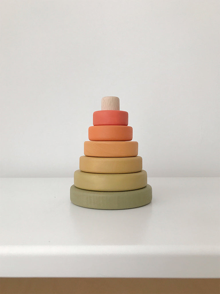 A Mini Wooden Pyramid Stacker - Flower Meadow consisting of six rings in gradient shades from dark green at the base to light orange at the top, painted with non-toxic paint, set against a plain white background.