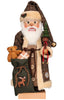 The Christian Ulbricht Collectible Wooden Nutcracker - Santa Claus in Brown Checkered Coat is a festive German nutcracker dressed as Santa, featuring a brown plaid coat and hat. It holds a small tree and a green sack with a reindeer design, and the limited-edition piece includes a teddy bear and a gift inside. The nutcracker is complete with white hair, a beard, and glasses.