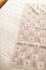 The Organic Cotton Baby Blanket - Fleur, featuring pink and cream patchwork, small floral designs, and lace edging, is neatly laid out on a soft white diamond-patterned quilted bedspread.