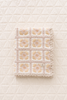 A beautifully quilted Organic Cotton Quilt - Daffodil, featuring soft beige and yellow tones reminiscent of sunflowers, is displayed on a cream-colored surface. Expertly crafted from organic cotton, this charming piece ships in one week and is perfect for little ones.