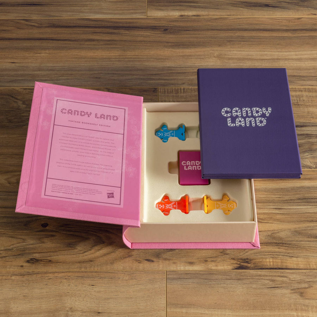 The Board Game: Candy Land Vintage Bookshelf Edition is open on a wooden surface, featuring colorful pieces and cards arranged in a pink and purple book-style box—a perfect family-friendly preschool game.