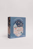 The "A Carnival of Wonders 100 Piece Puzzle" features whimsical carnival art, including a ferris wheel, tents, and performers. Made from recycled materials and suitable for ages 5+, it comes in a blue box.