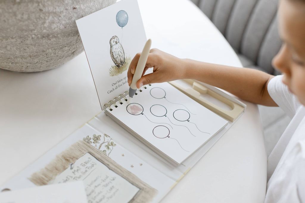 A child uses a water pen to reveal color on a balloon illustration of Owl in a Winnie-the-Pooh: Pooh’s Birthday Surprise (Water Reveal) book.