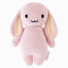 The Cuddle + Kind Baby Bunny is a hand-knit pink plush toy made from heirloom-quality Peruvian cotton yarn. It features long floppy ears, stitched facial details, and a small fabric tag, offering a soft texture and exquisite charm for any baby animal collection.