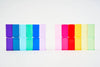 Two rows of colorful, transparent Bauspiel Luminous Blocks are displayed. The left set includes blue and purple blocks, while the right features red, pink, yellow, and green. Designed as high-quality educational building sets, they stand against a plain light background.