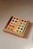 Bauspiel Gem Blocks with Lucent Cubes, 45-Piece Set, displayed as a wooden tray filled with wooden blocks featuring inlaid translucent colorful gems, alongside a stack of small transparent colored cubes.
