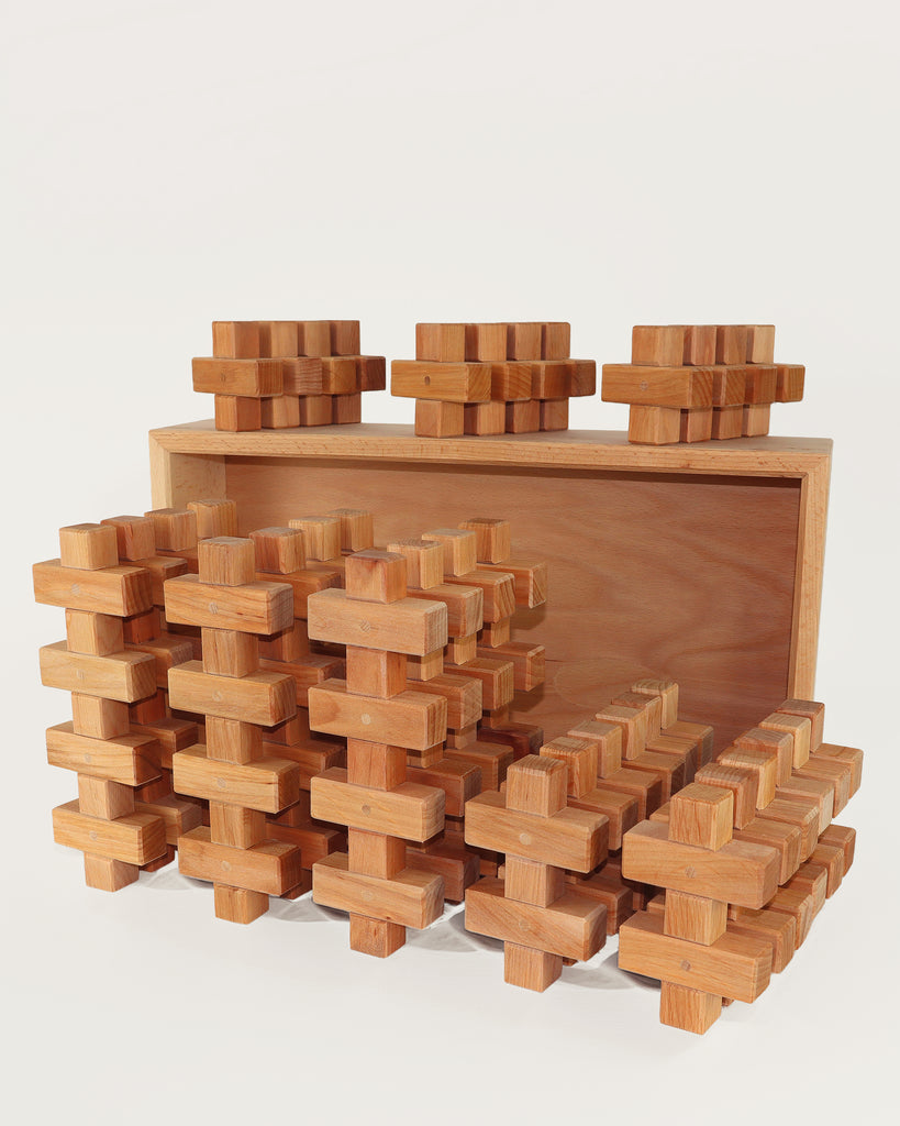 A set of thirty-six Bauspiel Plus Building Blocks, 36-Piece Set shaped like plus signs, some arranged in a wooden storage tray.