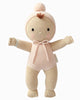 The Cuddle + Kind My First Baby (Blush) is a soft, hand-knit doll in a pale pink onesie and hood with pom-pom, rosy cheeks, stitched smile, and tuft of brown hair. Made from natural cotton yarn with outstretched arms. Ships in one week.